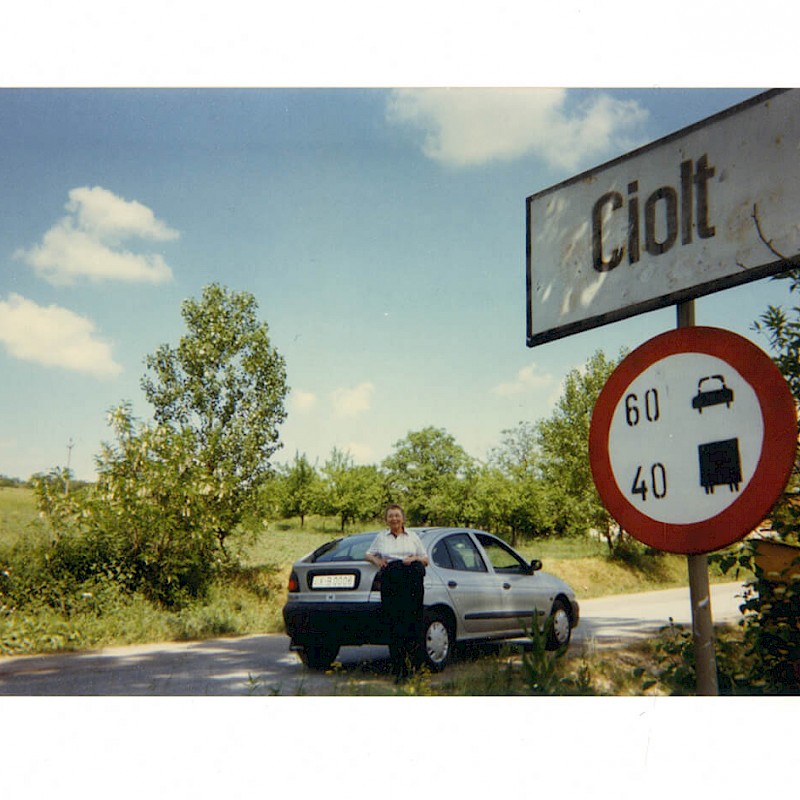 Gertrude posing by road sign in Ben's birthplace, Ciolt, Transylvania, June 1998